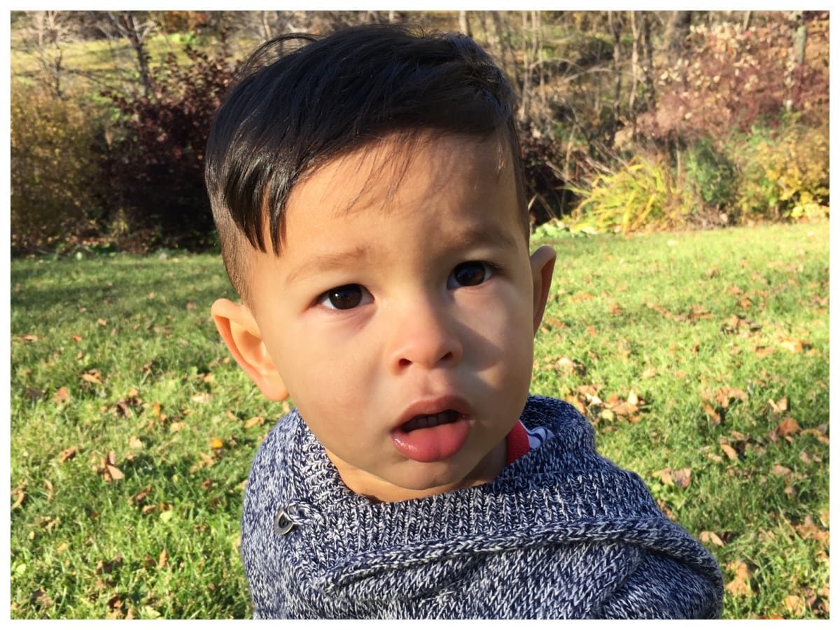 default-172 A boy sits outside on the grass and looks questioningly at the camera.